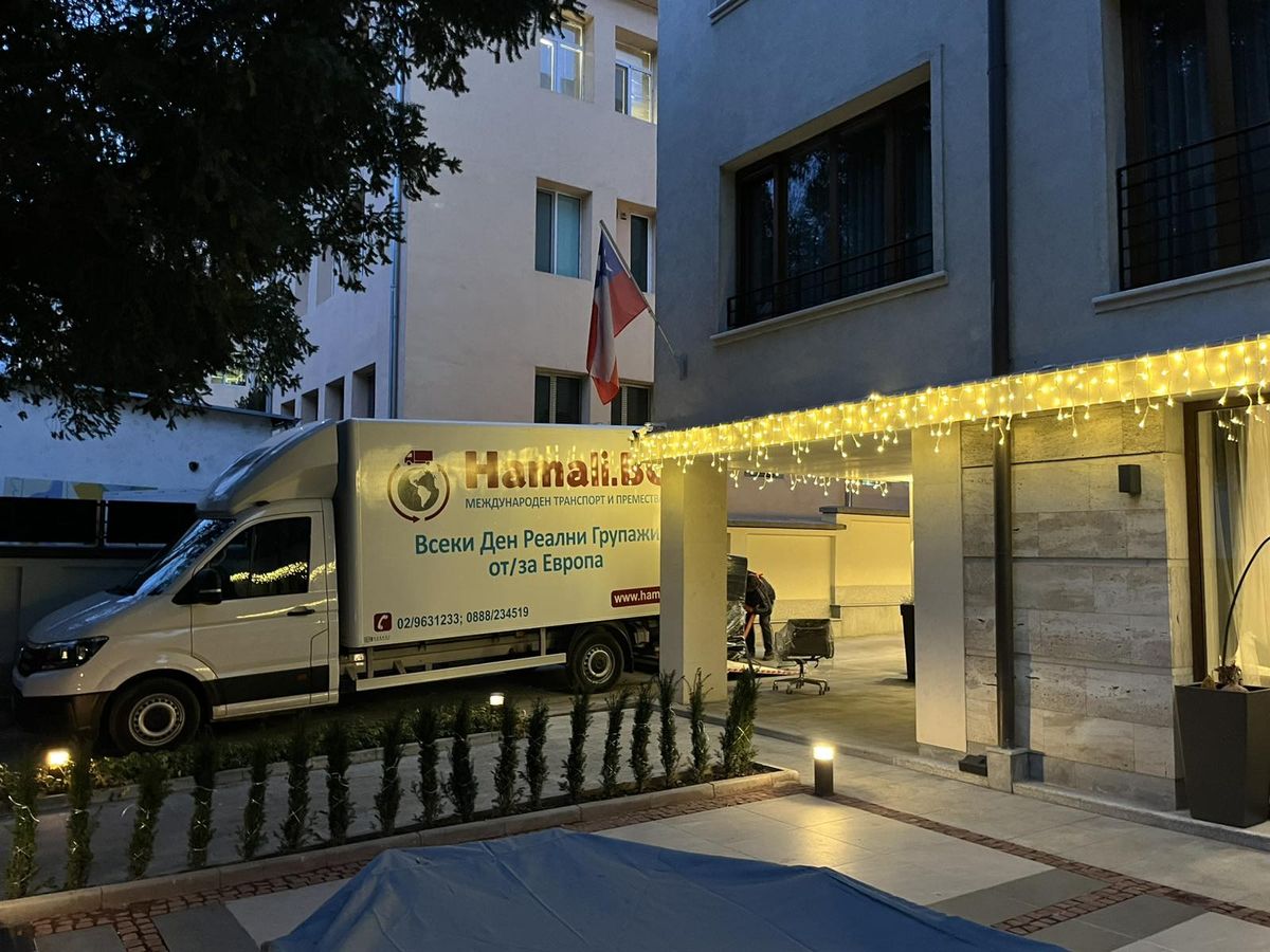 Un camion Hamali.BG lors d'un déménagement en soirée devant un bâtiment illuminé